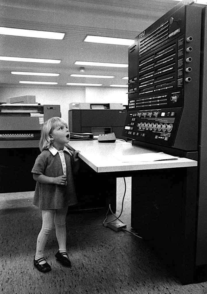 Young girl very amazed in front of an old 60s IBM mainframe.